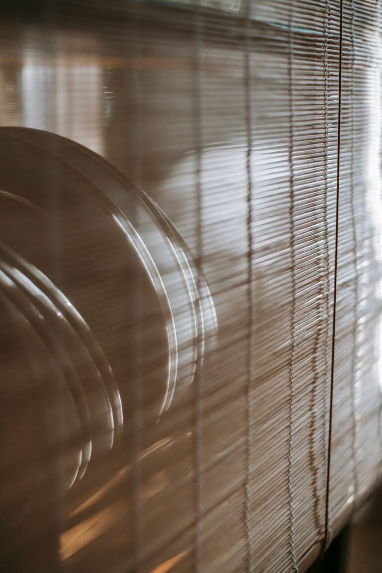 Clean plates placed on shelf behind decorative bamboo curtain in cozy apartment in daytime
