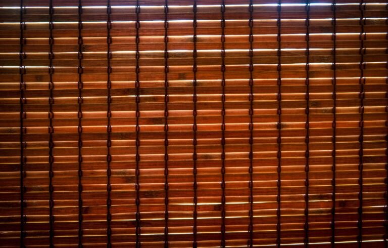 Detailed image of brown bamboo blinds with light filtering through, creating patterns.