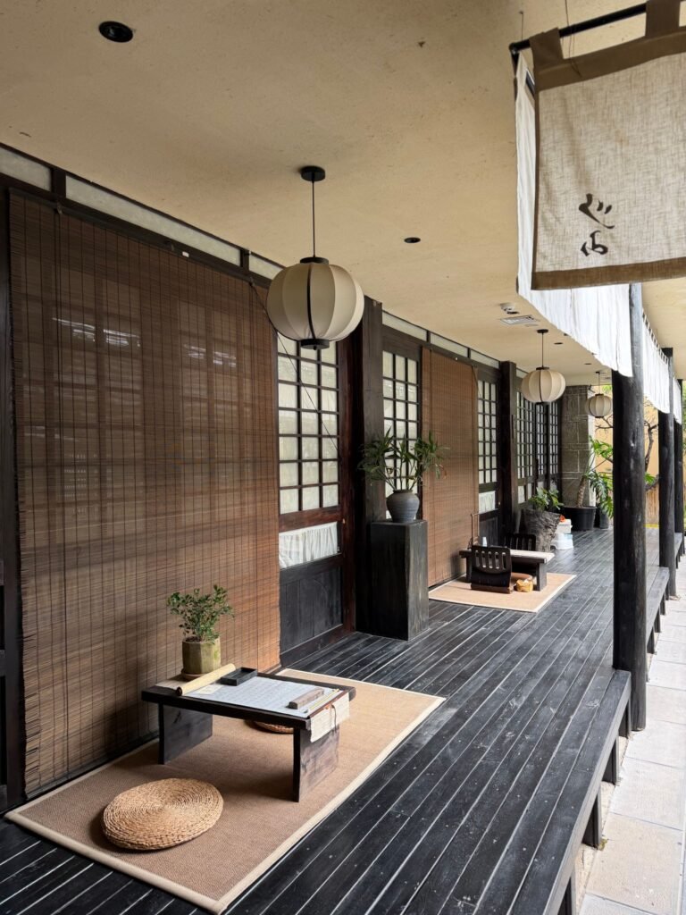 Elegant Asian outdoor hallway with minimalist decor, bamboo blinds, and paper lanterns creating a tranquil ambiance.