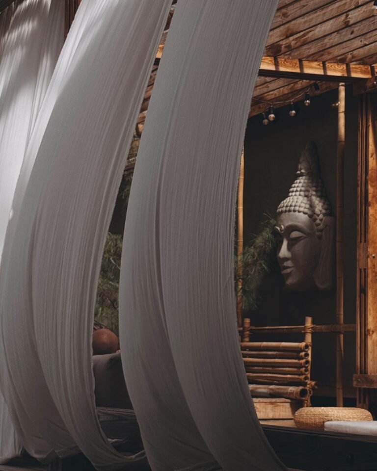 Peaceful outdoor seating area with flowing drapes and a serene Buddha sculpture for meditation and relaxation.